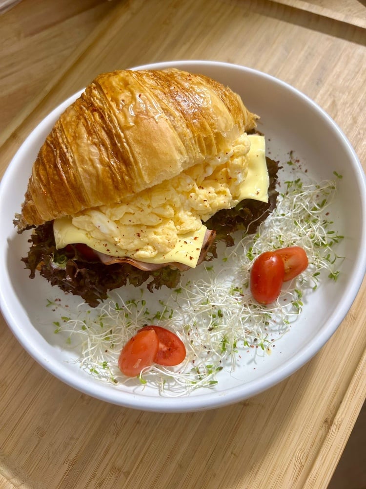 Breakfast croissant with cheese scramble with bacon/ham and tomato