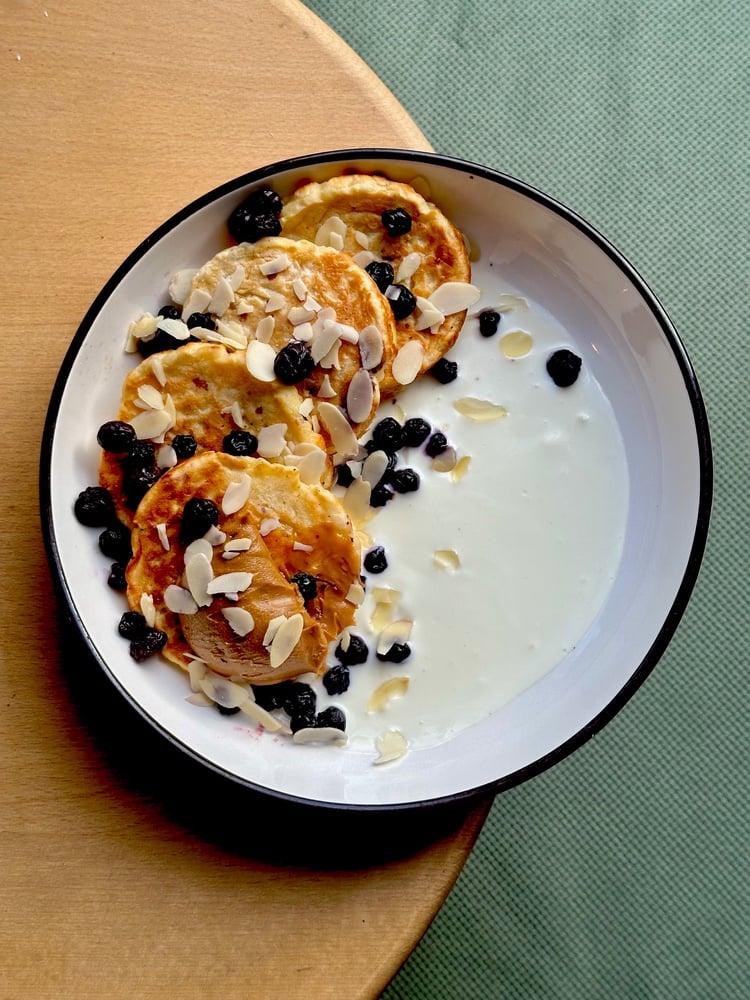 Яблучні оладки з ванільним кремом, пастою з печива лотус, лохиною і мигдальними пластівцями